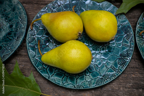 Top view of yellow pears on a green vintage plate on a wooden board