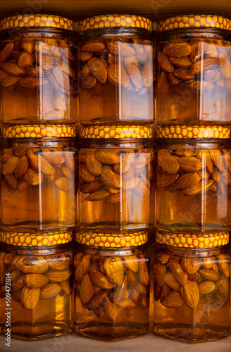 Various nuts in honey. Stand with products: Almonds nuts in honey or syrup in jars. Selective focus