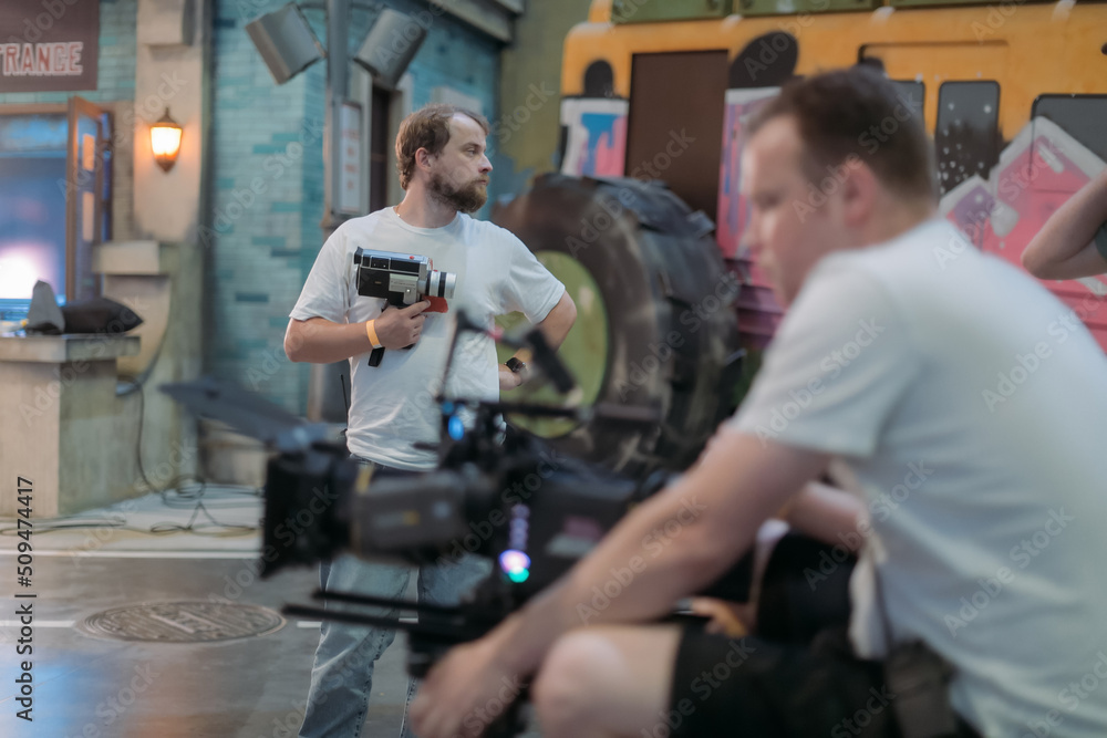 Director of photography with a camera in his hands on the set. Professional videographer at work on filming a movie Director of photography with a camera in his hands on the set. Professional videographer at work on filming a movie