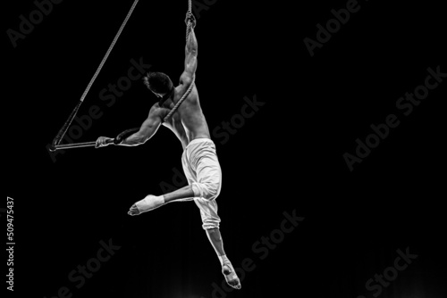 Muscular male air circus artist performances with dance trapeze  photo