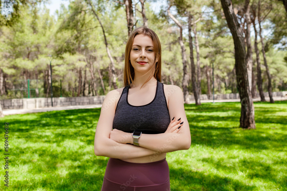 Beautiful brunette woman wearing sports bra standing on city park, outdoors Happy face smiling with crossed arms looking away with confident expression. Positive person, feels satisfied. Beautiful brunette woman wearing sports bra standing on city park, outdoors Happy face smiling with crossed arms looking away with confident expression. Positive person, feels satisfied.