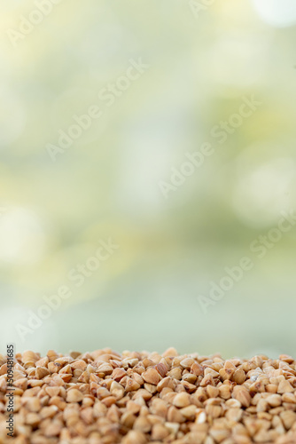Close up of buckwheat grains isolated on green summer background. Healthy food.