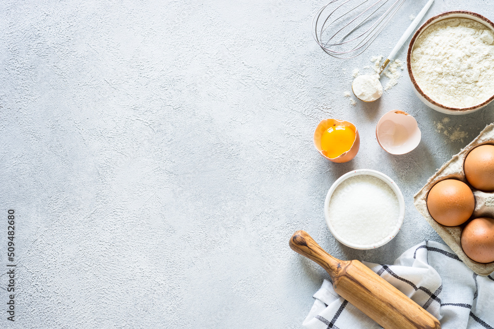 Baking background ingredients. Flour, sugar, eggs and rolling pin at light stone table. Top view with copy space. Baking background ingredients. Flour, sugar, eggs and rolling pin at light stone table. Top view with copy space.
