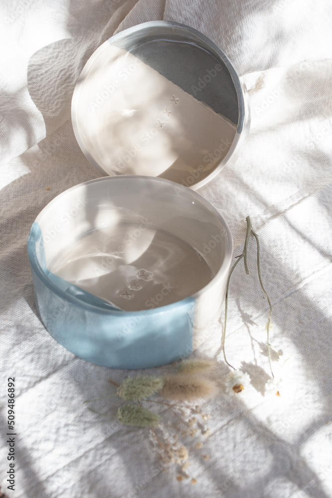 coloured ceramic vessels on white fabric and dried flowers coloured ceramic vessels on white fabric and dried flowers