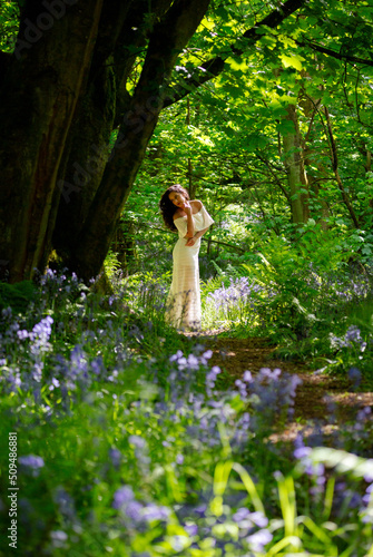 Indian girl in a long white dress walking through a Blue Bell wood