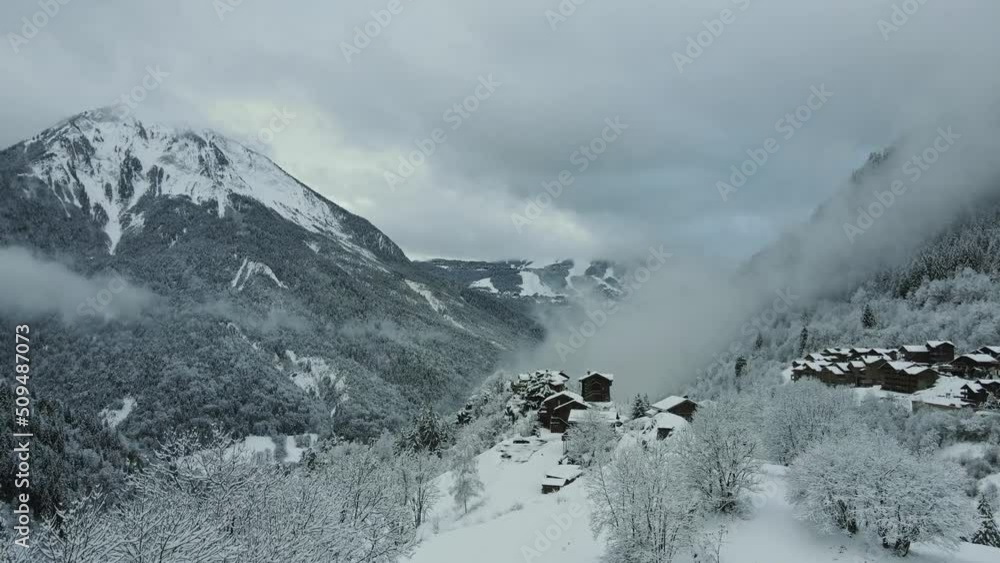 Winter mountains covered in snow and forest with wooden houses on the mountain top village above the clouds drone panorama. Winter mountains covered in snow and forest with wooden houses on the mountain top village above the clouds drone panorama.