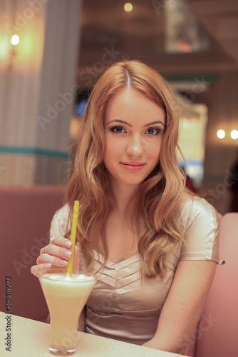 beautiful fashionable woman girl blond   in the room in a nice dress drink a coktail and smile