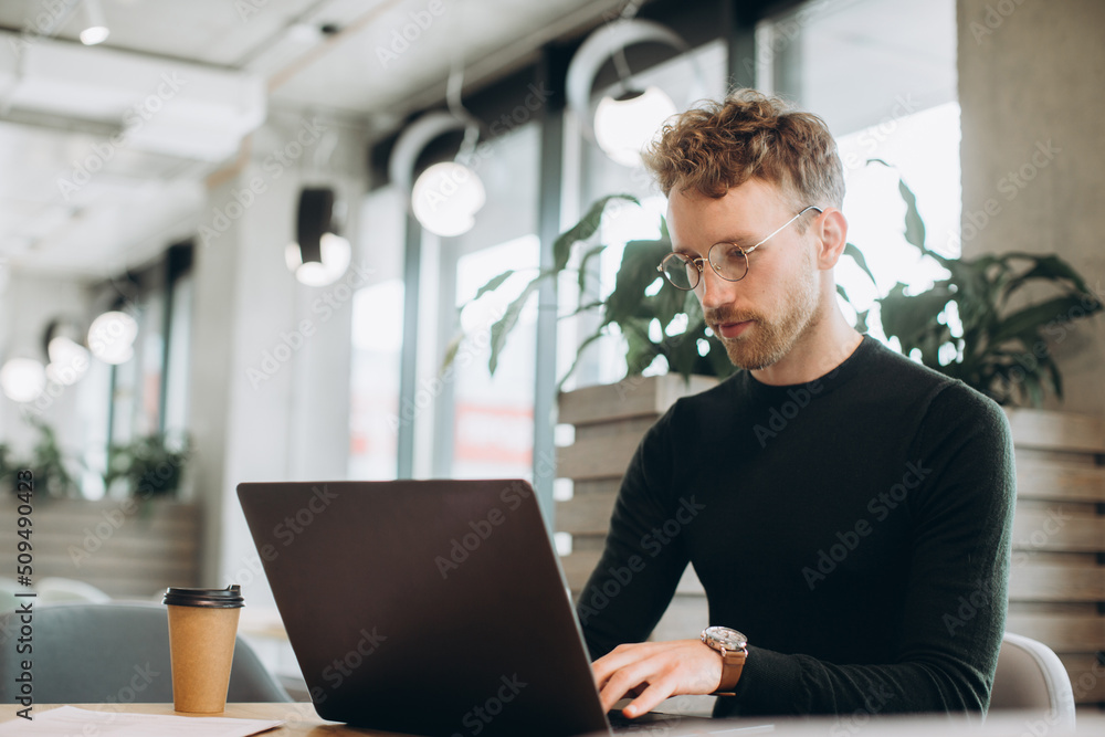 Man using laptop sitting at conference table in office Man using laptop sitting at conference table in office