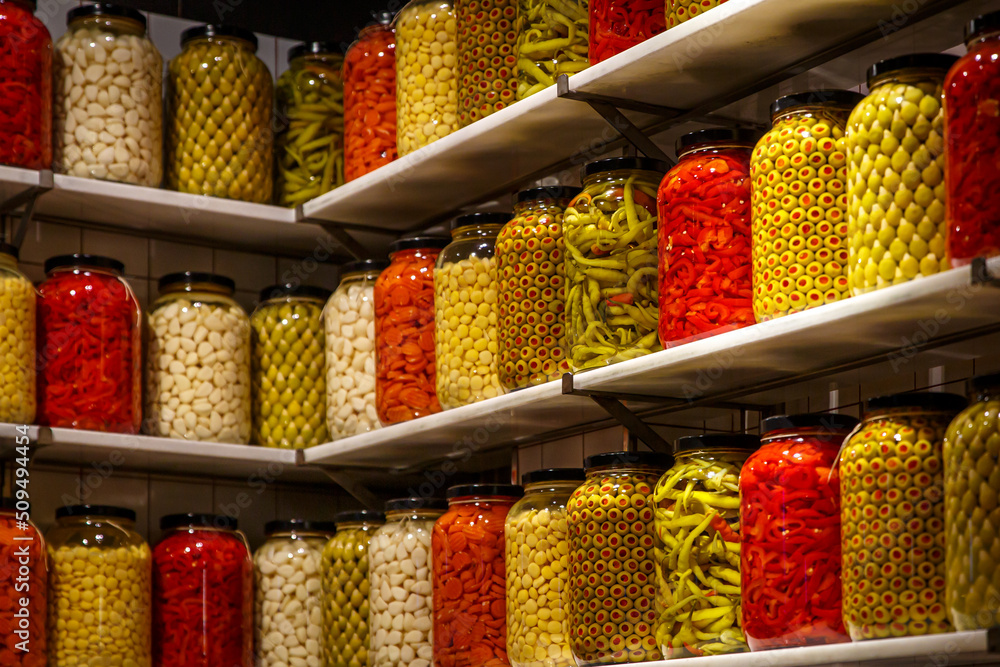 Pickled vegetables in jars on the shelf in the pantry.