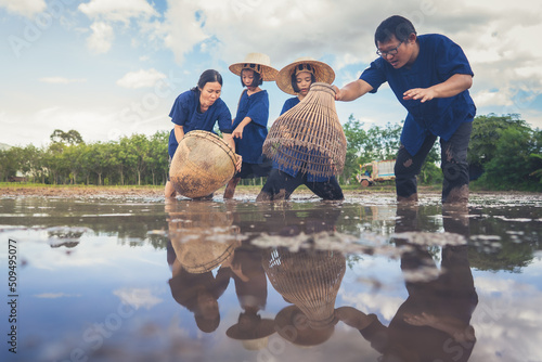 People family finding fish on tradition tool for catch fish in rice field of rural