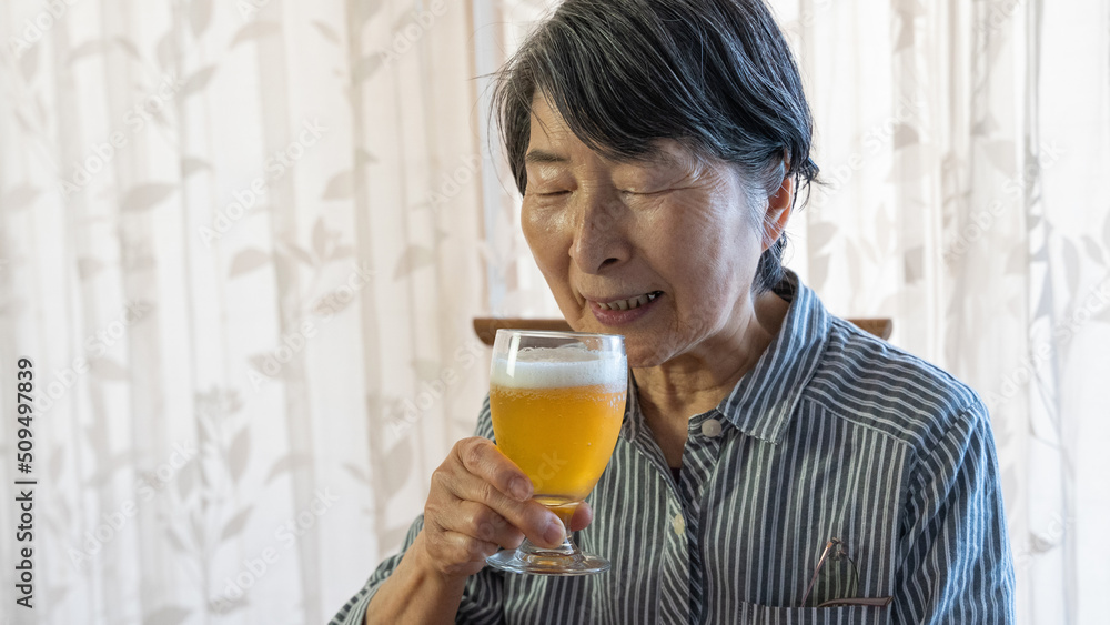 落ち着いた表情でビールを飲む老人女性