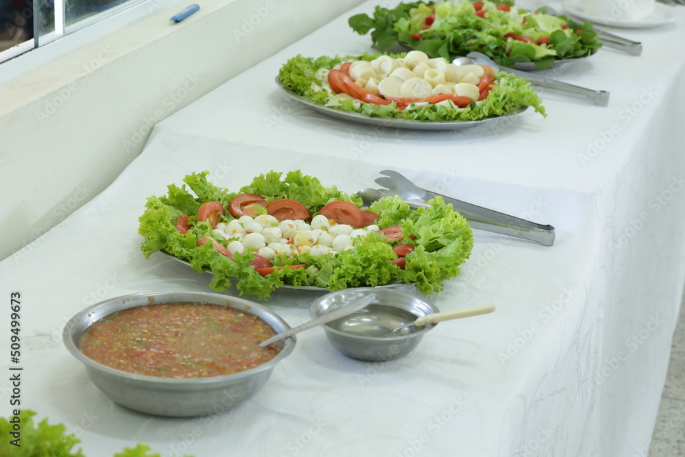 Prato com salada tomate e alface na mesa.