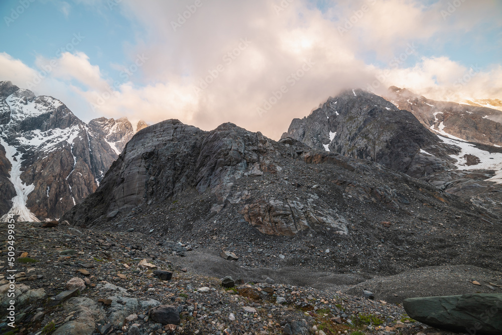 Scenic mountain landscape with sharp rocks in low clouds in golden sunrise colors. Awesome view to rocky mountain top in low clouds with golden dawn colors. Gold morning sunlight on high mountains.