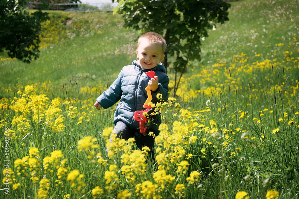 Active toddler running through blooming yellow meadow in spring. Childhood concept. Active toddler running through blooming yellow meadow in spring. Childhood concept.