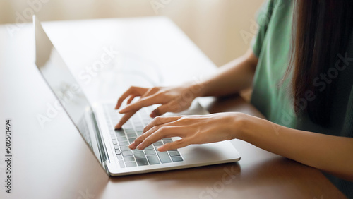 Hand of woman typing on computer laptop keyboard at house