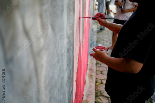 Close up hand of mural artist paint on the street wall