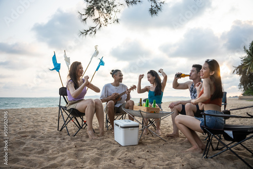 Fototapeta Group of Asian young man and woman having party on the beach together