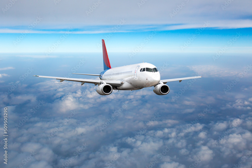 Front view of aircraft in flight. The passenger plane flies high above the clouds.