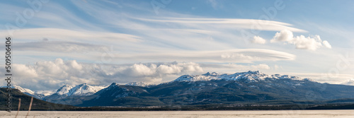 Panoramic shot of snow capped mountain view scenery seen in northern British Columbia during spring time with blue sky day and clouds. © Scalia Media