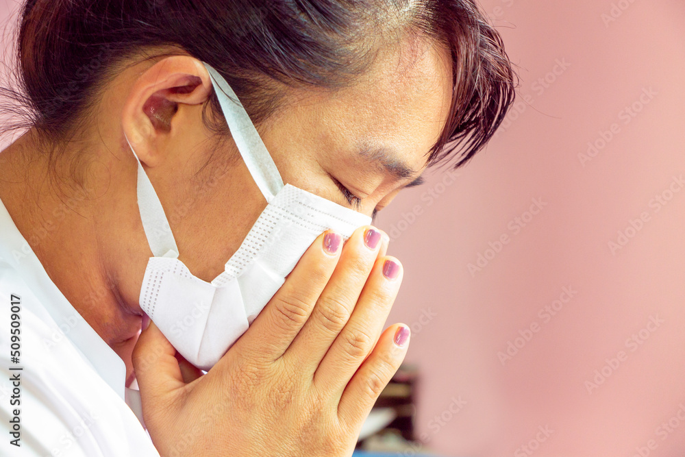 Closeup portrait of Asian lady wearing a face mask and putting a hand on her mouth because cough and illness. Health care concept. Closeup portrait of Asian lady wearing a face mask and putting a hand on her mouth because cough and illness. Health care concept.