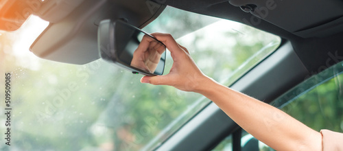 woman driver adjusting rear view mirror a car. Journey, trip and safety Transportation concepts photo