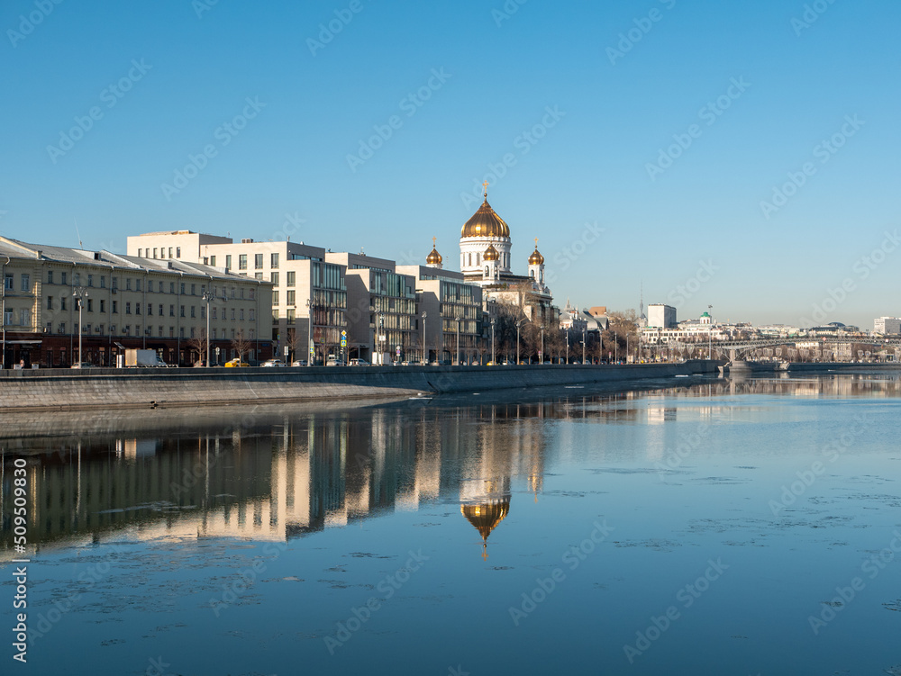 Beautiful view of the embankment of the Muzeon Park and the Cathedral of Christ the Savior against the blue sky. Houses are reflected in the Moscow River. Copy space. Moscow, Russia