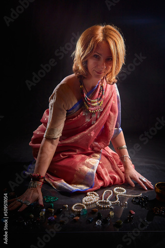 A beautiful European woman in a traditional Indian sari on a black background. Girl model posing in the studio