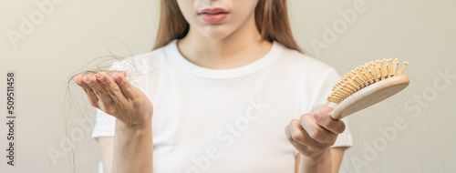 Serious, worried asian young woman, girl holding comb, show her hairbrush with long loss hair problem after brushing, hair fall out problem. Health care, beauty with copy space on white background.