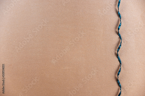 Black spiral cord opposite the brown background. A thin black rope hangs vertically. Minimalist background with copy space for text and design elements