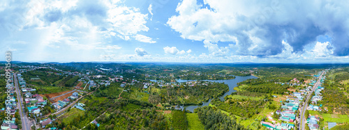 Aerial panorama view of National Route 14 in Kien Duc town, Dac Nong province, Vietnam with hilly landscape, sparse population around the roads and Dak R'tang lake.