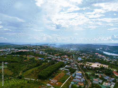 Fototapeta Naklejka Na Ścianę i Meble -  Aerial view of National Route 14 in Kien Duc town, Dac Nong province, Vietnam with hilly landscape and sparse population around the roads.