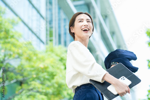 オフィス街に立つ笑顔の女性