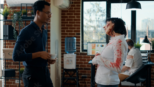 Canvas Print Hungry creepy zombie talking with businessman while dead coworker covered in blood walks by