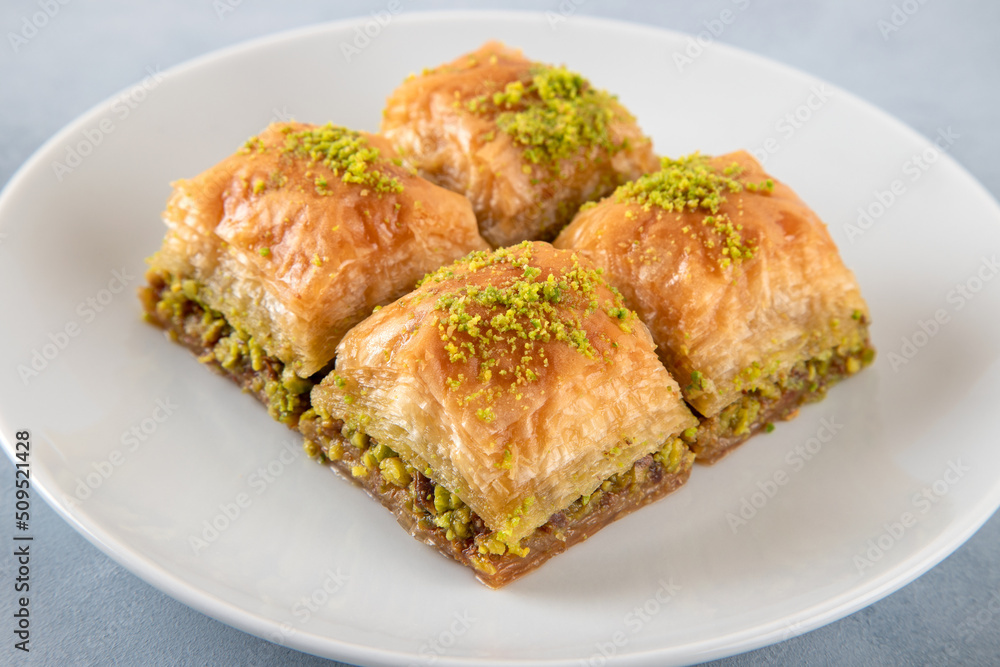 Pistachio baklava on a white plate.Traditional Turkish baklava on a white background
Pistachio baklava on a white plate.Traditional Turkish baklava on a white background