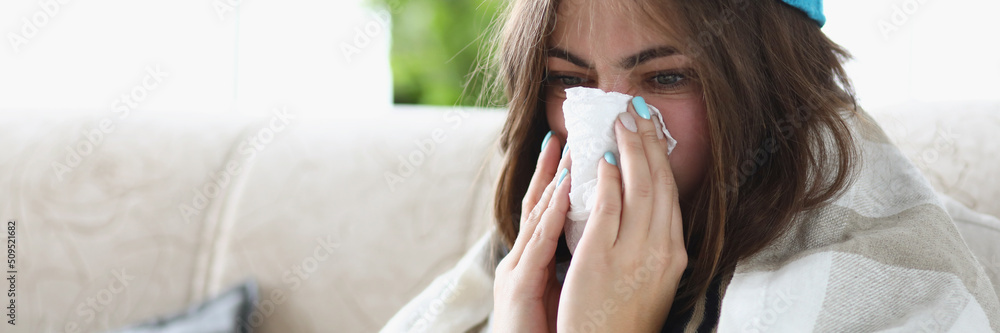 Woman wipe wet running nose with tissue dressed in warm clothes because of cold Woman wipe wet running nose with tissue dressed in warm clothes because of cold