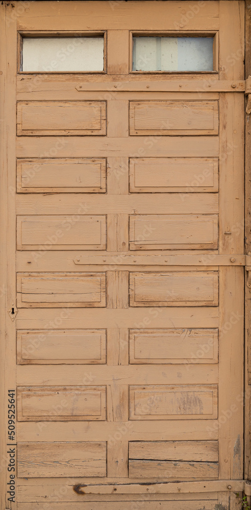 Front view of an old and weathered wooden door painted in beige or light brown. Abstract high resolution full frame textured background. Front view of an old and weathered wooden door painted in beige or light brown. Abstract high resolution full frame textured background.