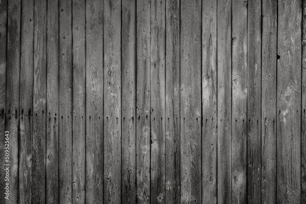 Front view of an old, weathered and dark wooden wall in black and white. Abstract full frame textured background. Front view of an old, weathered and dark wooden wall in black and white. Abstract full frame textured background.