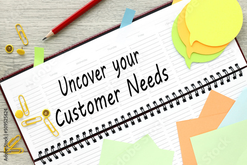 uncover your customer needs. text on planner on wooden background