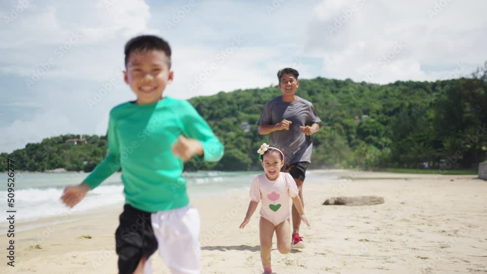 4K Happy Asian family grandfather jogging exercise with little grandchild boy and girl on tropical beach. Healthy senior man and children kid enjoy outdoor activity sport training on summer vacation