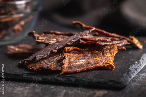 Beef jerky meat. Dried sliced meat on cuting board.