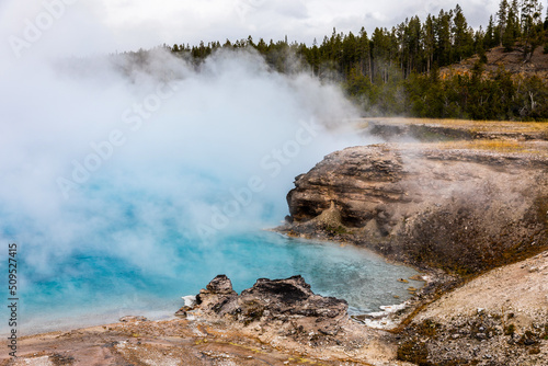 Blue pond with smoke inside dangerous hot zone in Yellowstone.