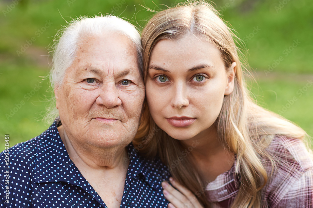 Close up portrait of two generation women, grandmother and granddaughter outdoors Close up portrait of two generation women, grandmother and granddaughter outdoors