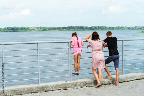 Mom with teenage children are standing on the embankment admiring the bay. unrecognizable person