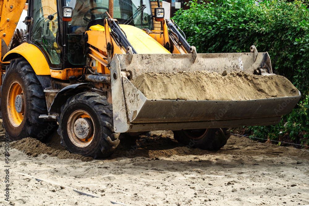 A bulldozer loaded with sand is working on a construction site. Close-up