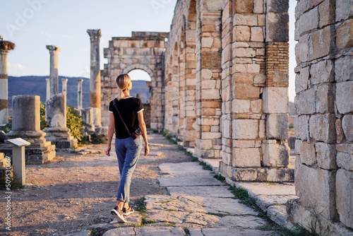 Happy young woman walking on ancient antique city Volubilis. Traveling by Morocco.