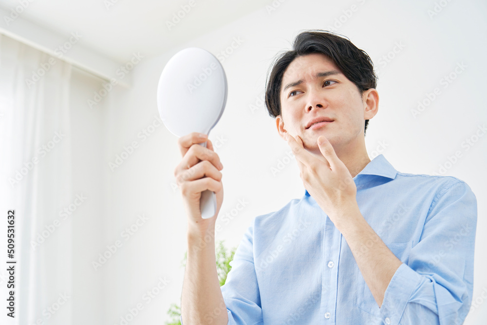 鏡で顔をチェックする男性 鏡で顔をチェックする男性
