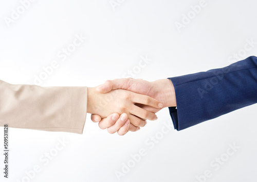 白バックで握手するビジネスウーマンとビジネスマンの手元