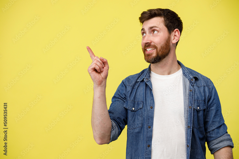 Smiling man looking at side with raising his finger up and pointing to empty space Smiling man looking at side with raising his finger up and pointing to empty space