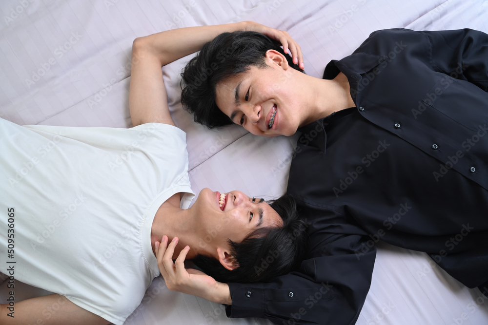 Overhead view young gay couple lying down on bed, spending time together. LGBT, pride, relationships and equality concept