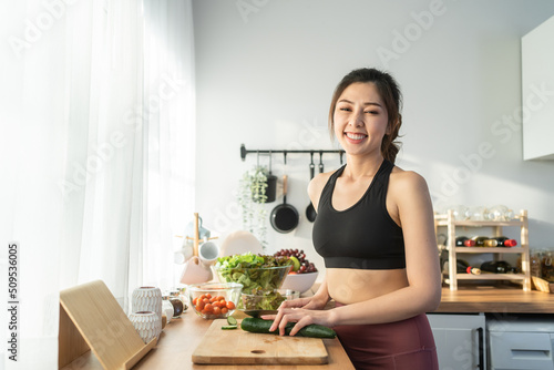 Portrait of Asian attractive woman cooking salad and look at camera. 